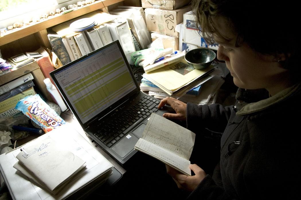 Small business managing spreadsheet data and manual records on laptop